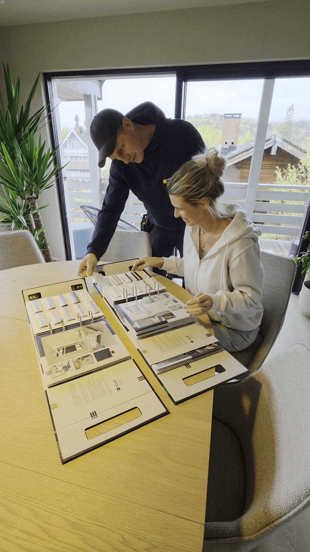 Nichlas og ansatt blar i produktkatalog mens de ser på sesongens materialer